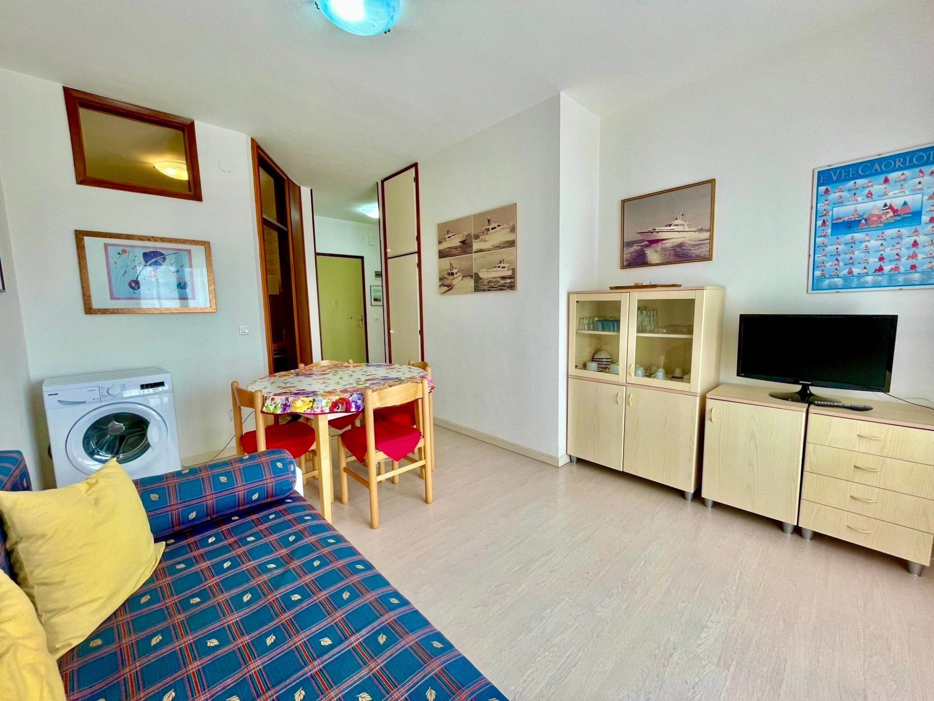 A room with a bed, a table, a cabinet, a TV, and a washing machine.