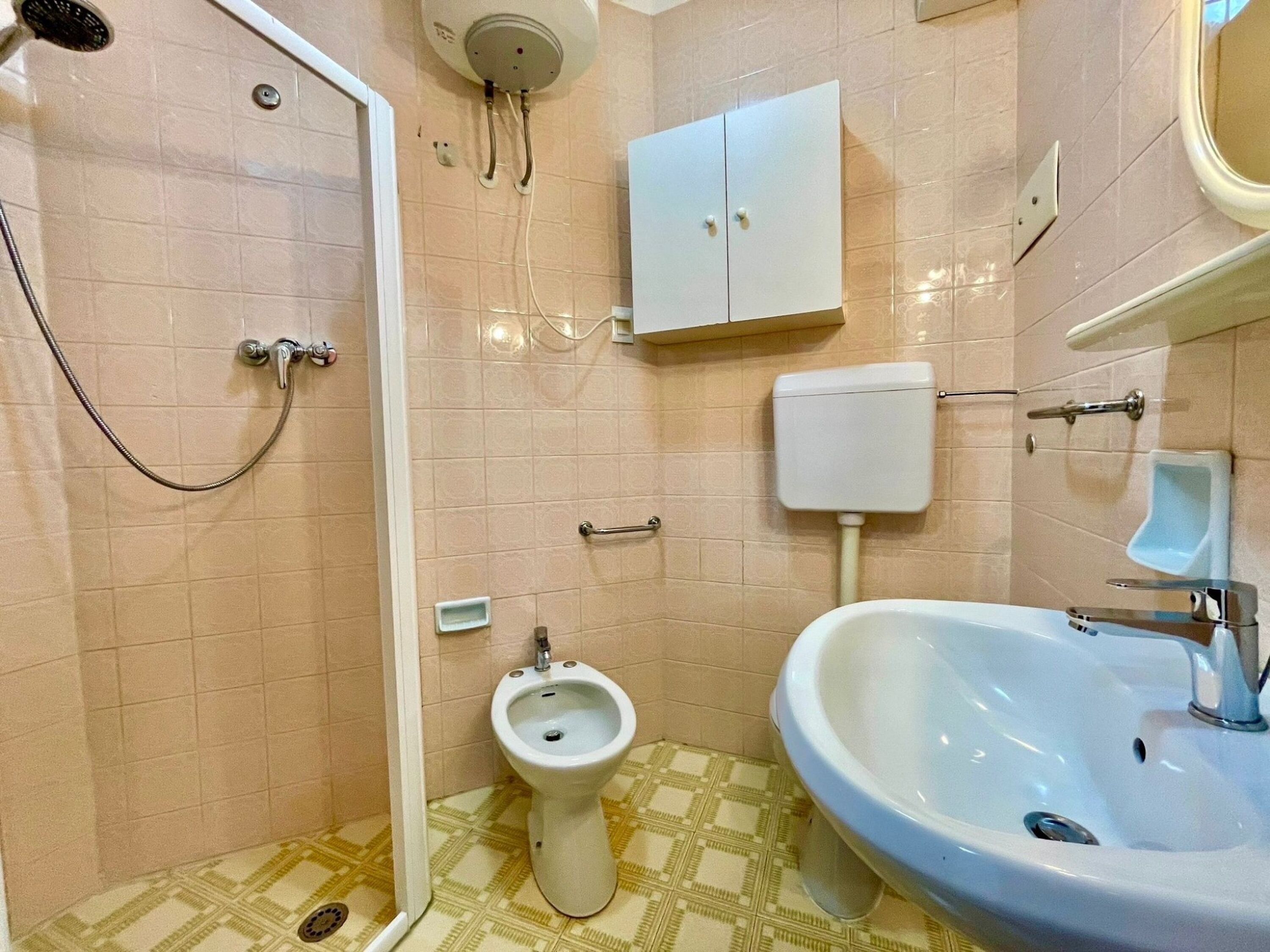 Une salle de bain équipée d’une douche, de toilettes, d’un bidet et d’un lavabo.