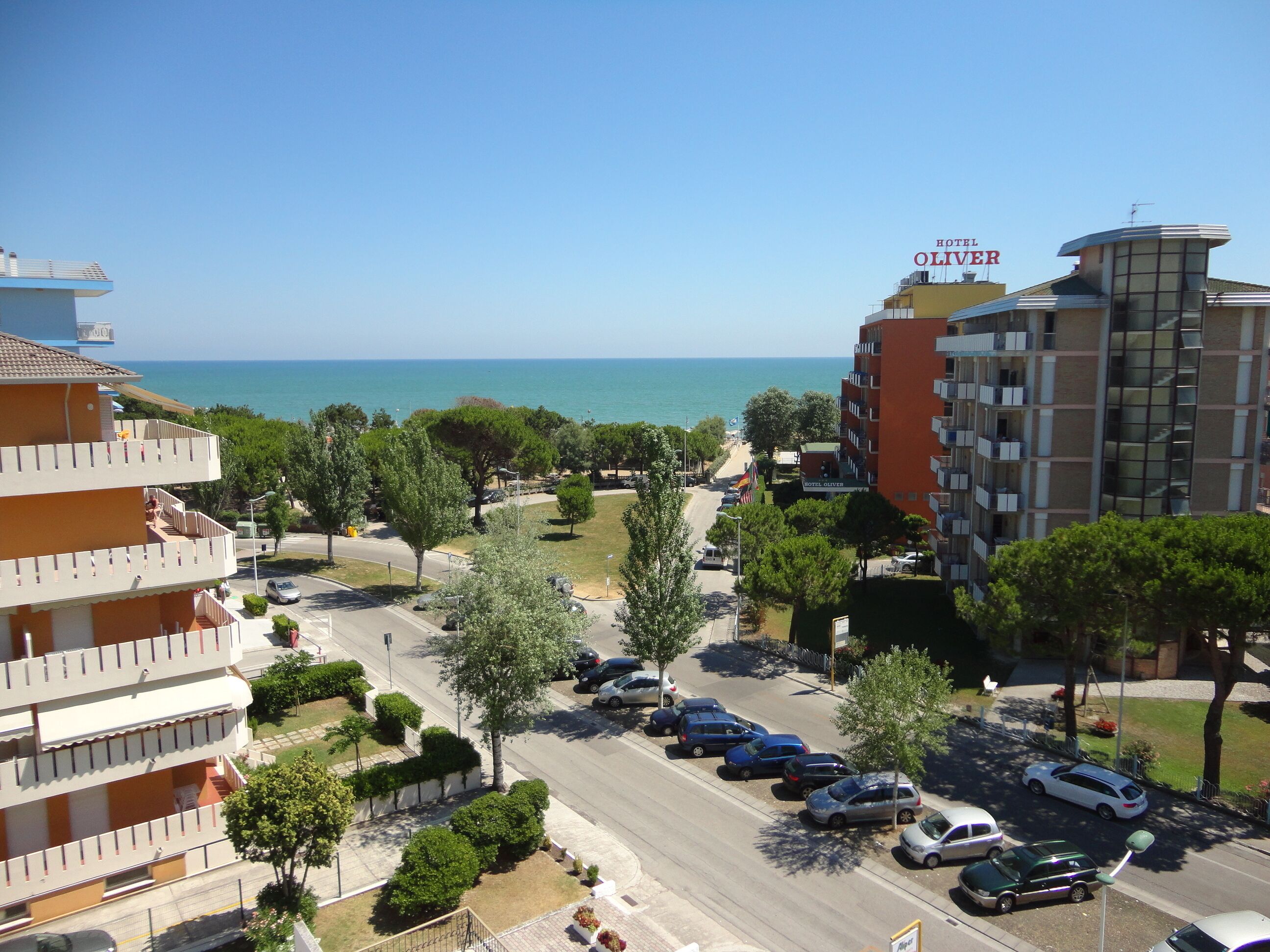 Un hotel con vista al mar, varios espacios de estacionamiento y una calle con coches.