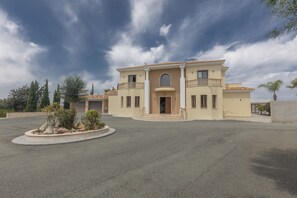 A two-story building with a central entrance, balconies, and a landscaped area with plants.