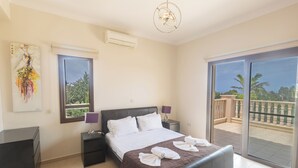 A hotel room with a bed, a desk, a chair, a window, and a balcony. - Protaras Holiday Villa Pa7 Private 7 Bedroom Villa (Paralimni)