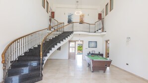 A spacious indoor area with a curved staircase, a pool table, and a door leading to another room. - Protaras Holiday Villa Pa7 Private 7 Bedroom Villa (Paralimni)