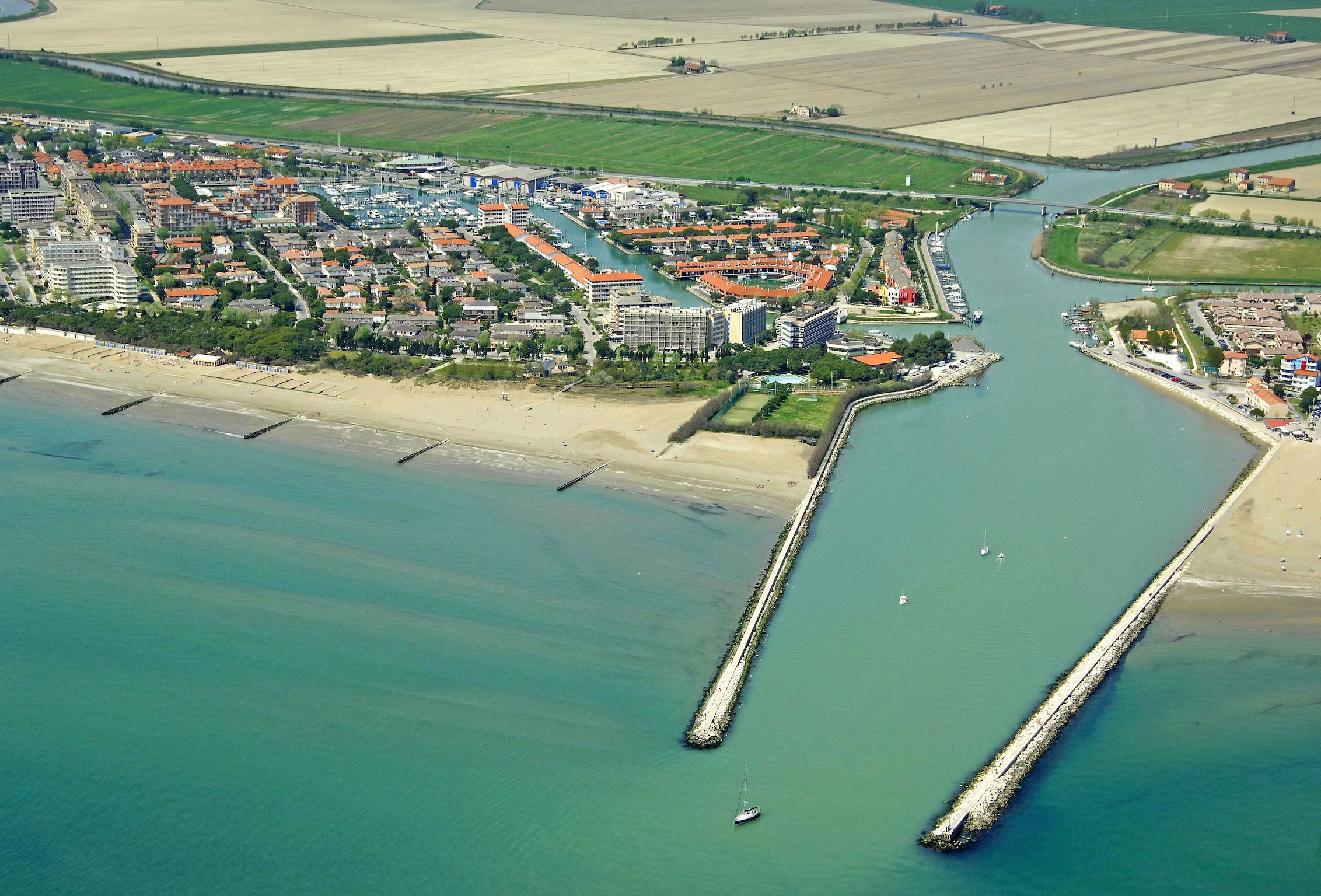 An aerial view of a coastal town with a marina, beach, and residential buildings.