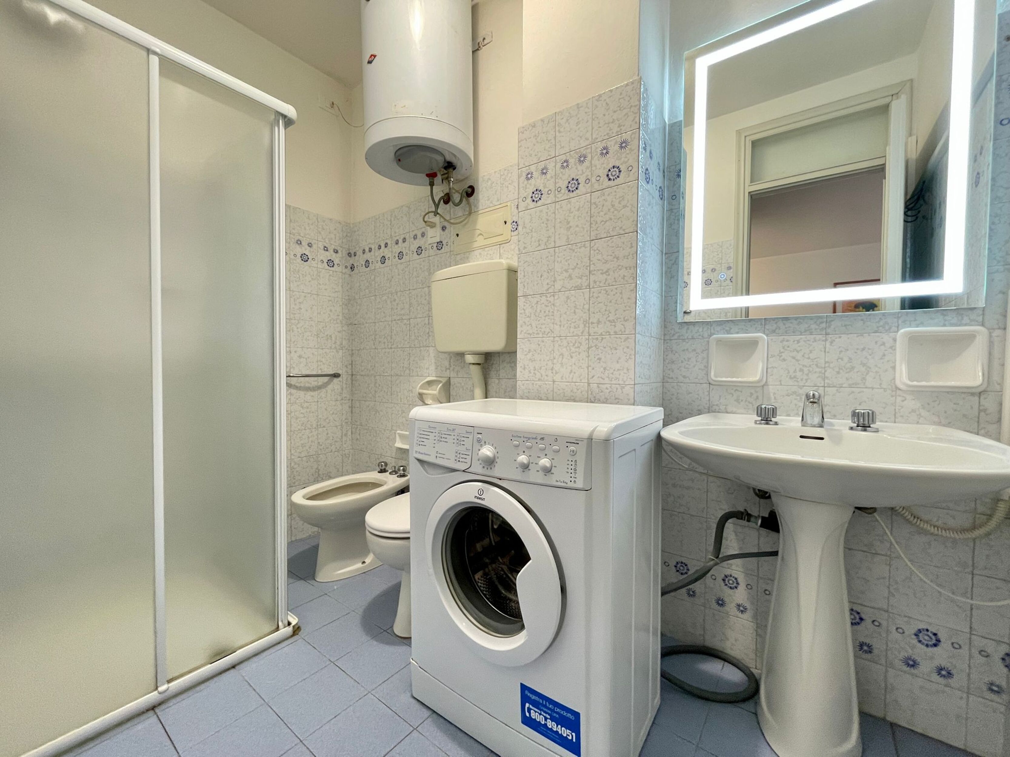 A bathroom with a washing machine, toilet, and sink.
