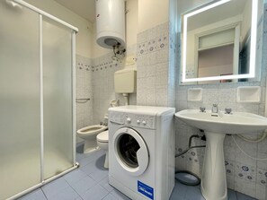 Kylpyhuone, jossa on pesukone, wc ja pesuallas.