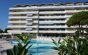Un hôtel à plusieurs étages doté de balcons, d’une piscine et d’une végétation luxuriante.