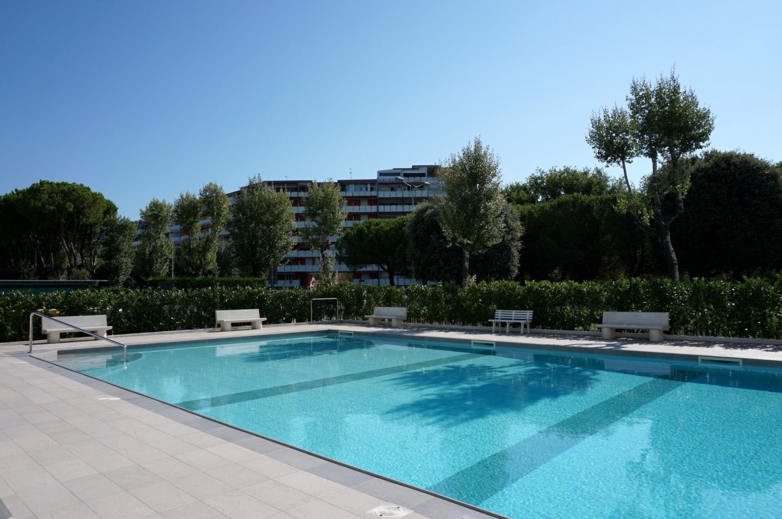 A swimming pool with benches and a clear sky.