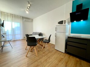 A modern kitchen with a built-in microwave, a refrigerator, and a flat-screen TV mounted on the wall. - Modern Apartment With Pool and sea View (Caorle)