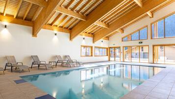 Une piscine intérieure avec des poutres en bois et de grandes fenêtres.