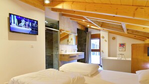 A hotel room with two beds, a TV, a bathroom with a bathtub, and a shower. - Chalet in French Alps near Lake Geneva (Abondance)