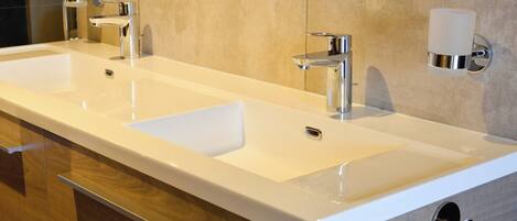 A modern bathroom with a double sink, chrome fixtures, and a towel rack.