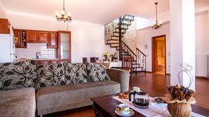 A living room with a sofa, a coffee table, and a staircase leading to an upper floor. - Luxury Endless Sea View Escape (Plaka)