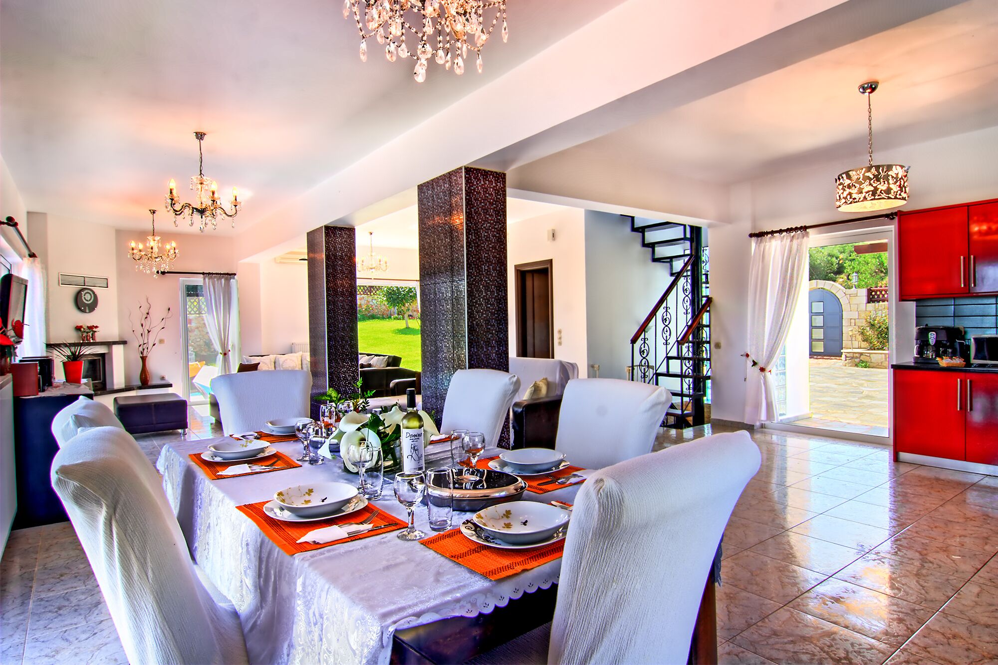 A dining area with a table set for four, a chandelier, and a view of the outdoors.