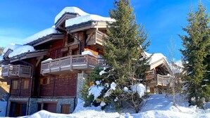 Un chalet en bois doté de plusieurs balcons, entouré d’arbres couverts de neige.
