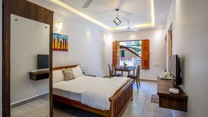 A bedroom with a bed, bedside table, TV, and a painting on the wall. - Whiteboard Homes (Siolim)