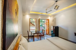 Ein Hotelzimmer mit Bett, Schreibtisch mit Stühlen, Fernseher und Balkon mit Außenblick.