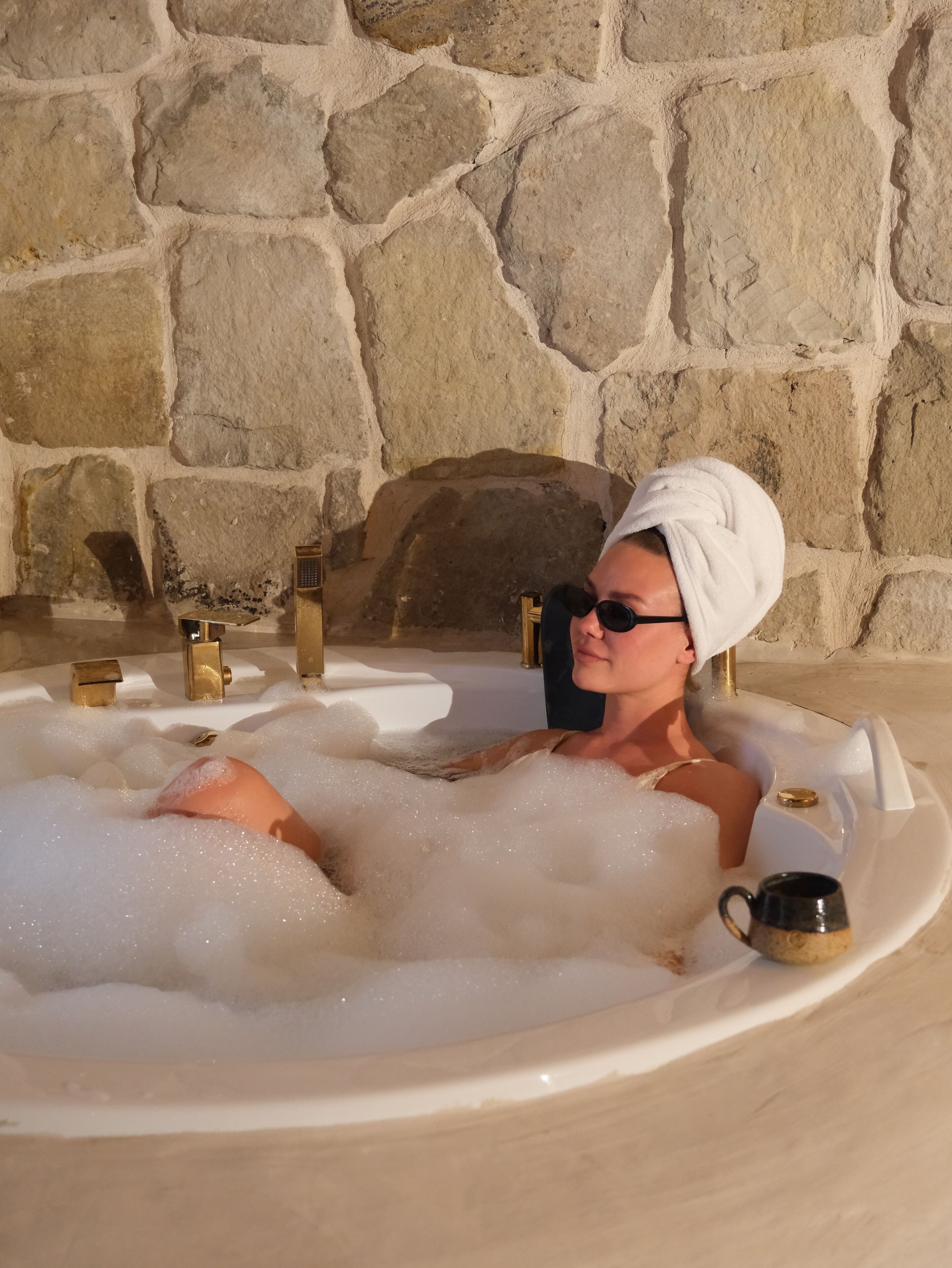 A person in a hot tub with a stone wall background.