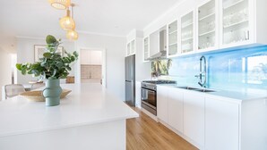 Una cocina moderna con armarios blancos, una isla central, una estufa y un fregadero.