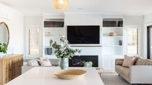 Una sala de estar moderna con una chimenea blanca, un televisor de pantalla plana y una estantería llena de libros.