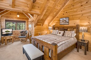 Una camera da letto accogliente in legno con un letto di legno, una scrivania con un computer, una sedia e una panca.