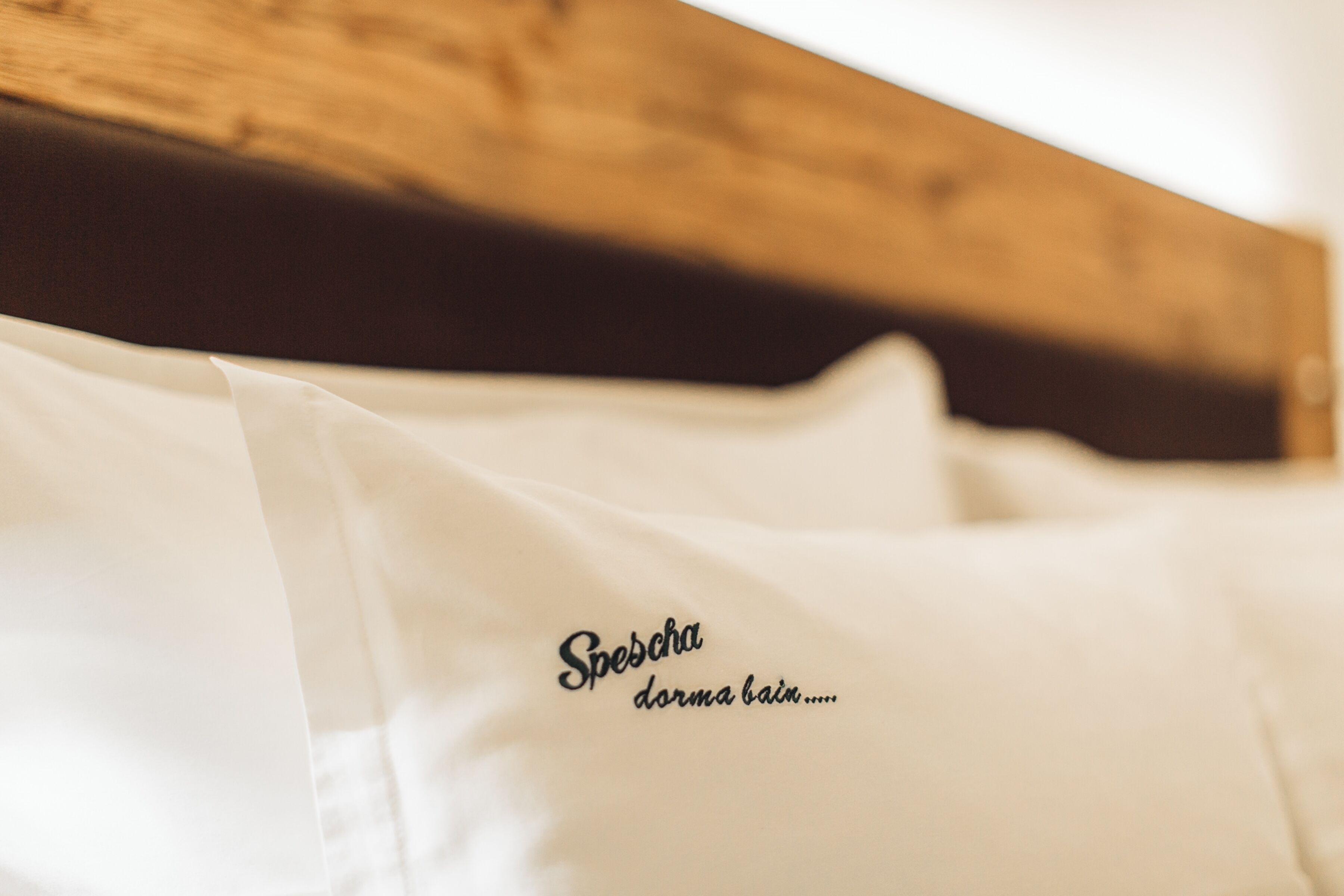 A bed with white linens and a wooden headboard.