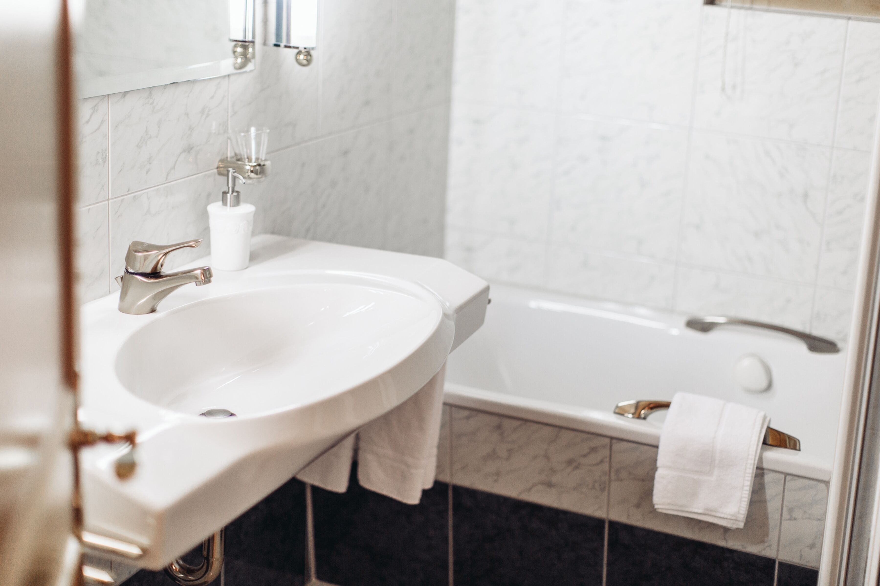 Une salle de bain avec un lavabo blanc, un miroir et une baignoire.