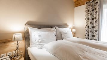 Habitació d'hotel amb un llit, una làmpada de nit, un telèfon i una finestra amb cortines florals.
