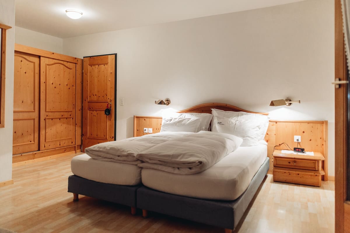 Une chambre à coucher avec un grand lit, une armoire en bois et des tables de chevet avec des lampes.