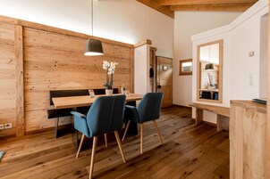 Una habitación moderna con paredes y suelos de madera, una mesa de comedor de madera con sillas azules, un banco y un espejo.
