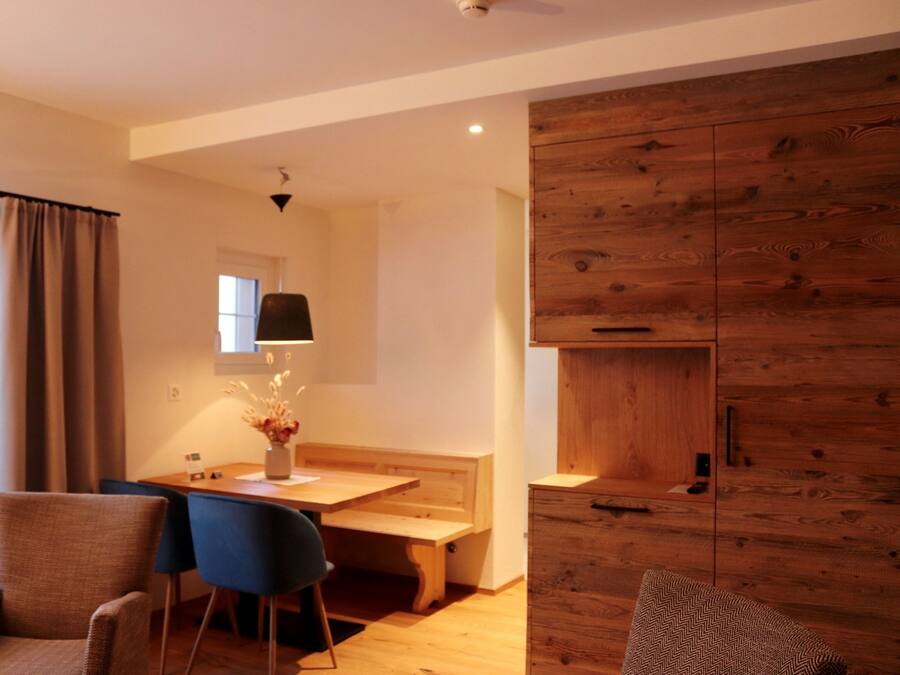 Una sala de estar moderna con un mueble de madera, una mesa de comedor con sillas y un banco.
