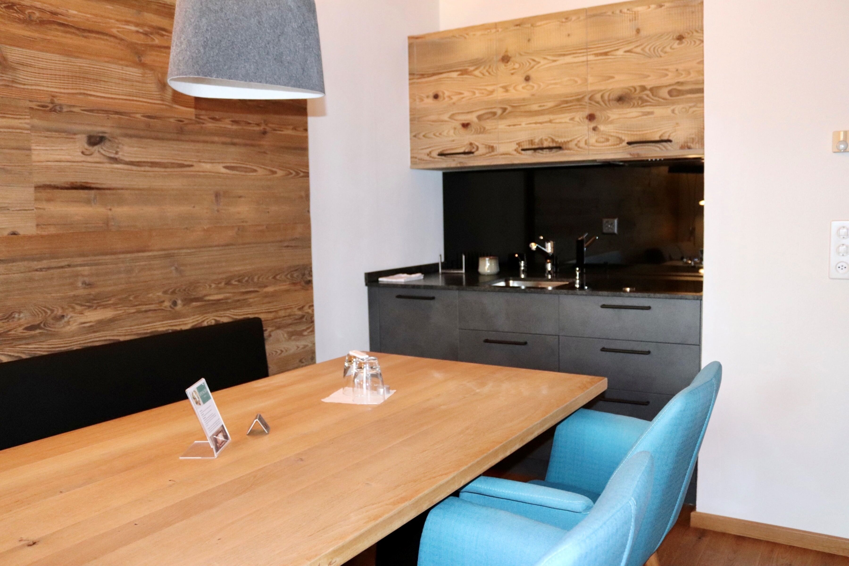 A modern kitchen with wooden wall paneling, a black countertop, and a built-in stove.