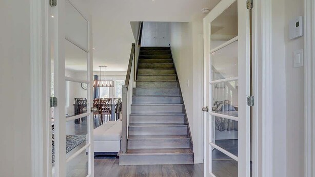 Eine Treppe führt zu einer zweiten Etage mit modernem Design, weißen Wänden und Holzboden.