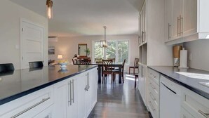 Eine moderne Küche mit weißen Schränken, einer großen Kochinsel und einem Essbereich mit Tisch und Stühlen.