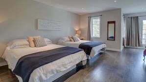 Ein Schlafzimmer mit zwei Betten, einem großen Fenster und einem Spiegel an der Wand.