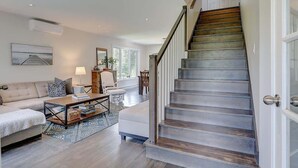 Ein modernes Wohnzimmer mit Treppe, Sofa, Couchtisch und Essbereich.