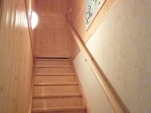 Uma escada de madeira com corrimão, que leva a um patamar com um relógio fixado na parede.