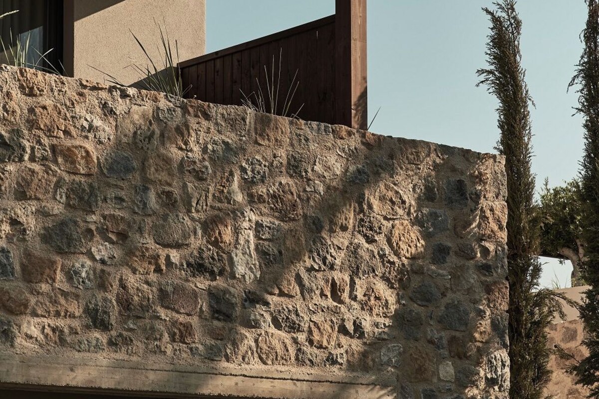 A stone wall with a wooden pergola structure.