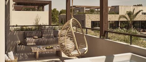Une terrasse sur le toit équipée d’un jacuzzi, d’un fauteuil suspendu, d’un canapé et d’une table basse.