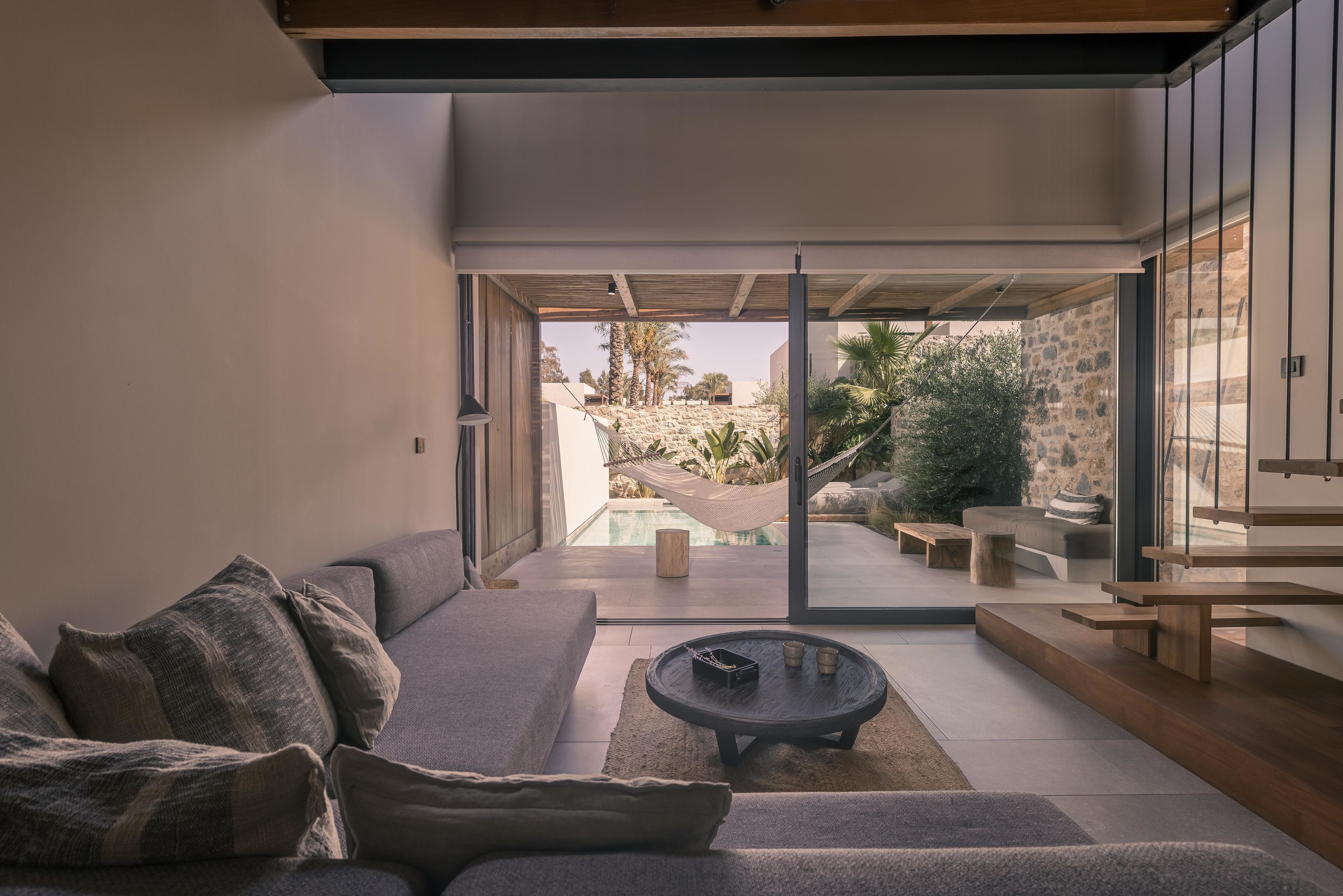 Un salon moderne avec un canapé, une table basse et une vue sur un espace piscine extérieur.