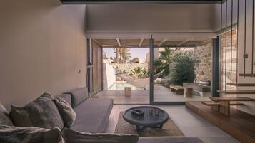 Un salon moderne avec un canapé, une table basse et une vue sur un espace piscine extérieur.