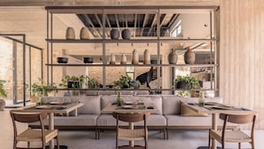 A modern interior with a dining area, sofas, and a display of pottery. - Theros All Suite Hotel - Adults Only (Kos)
