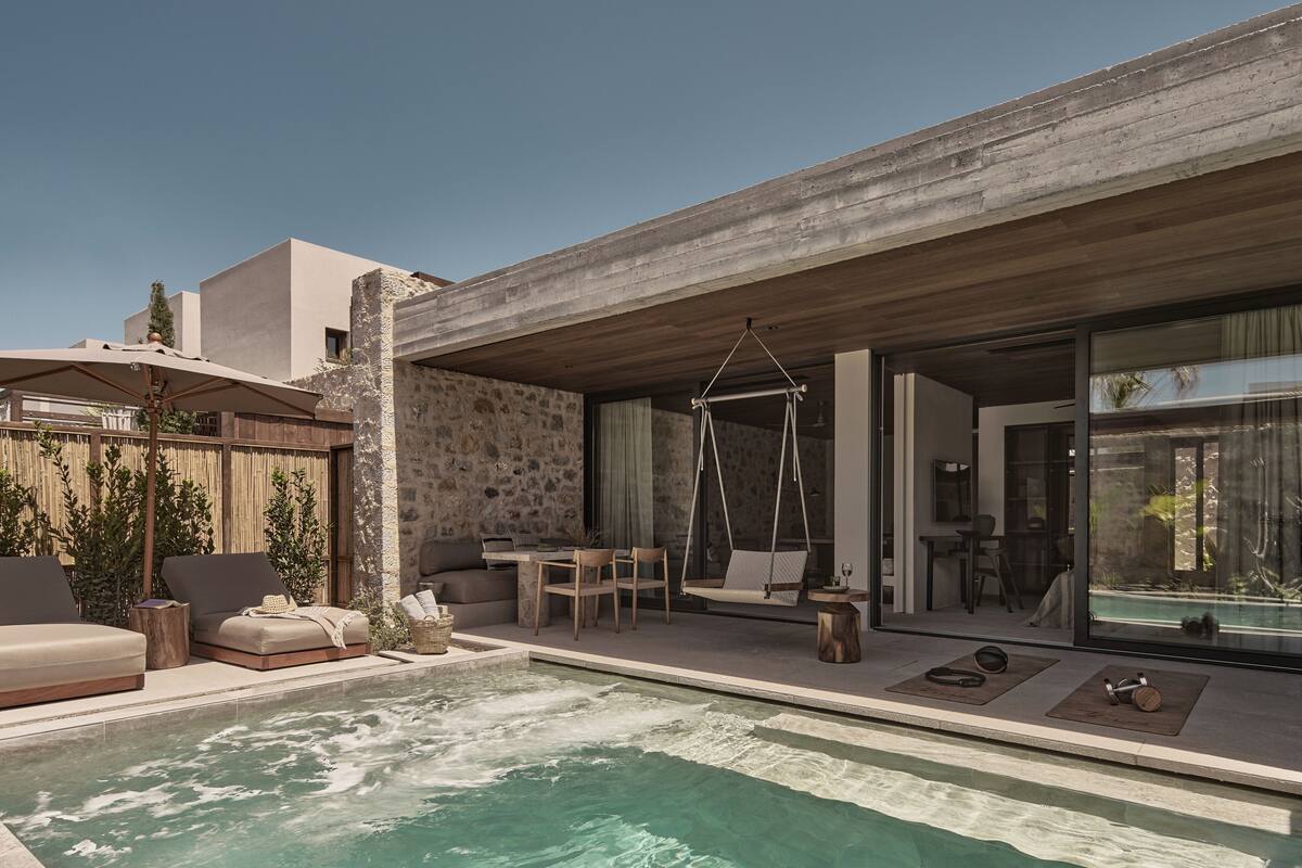 Un área de piscina moderna al aire libre con sillones de descanso, una hamaca y una zona de comedor.