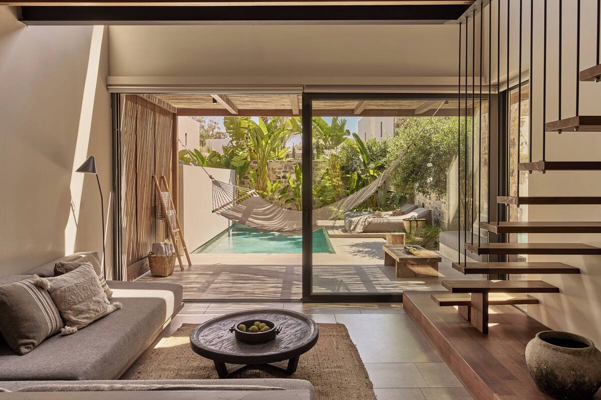 Un salón moderno con un sofá, una mesa de centro y vistas a un área de piscina al aire libre.