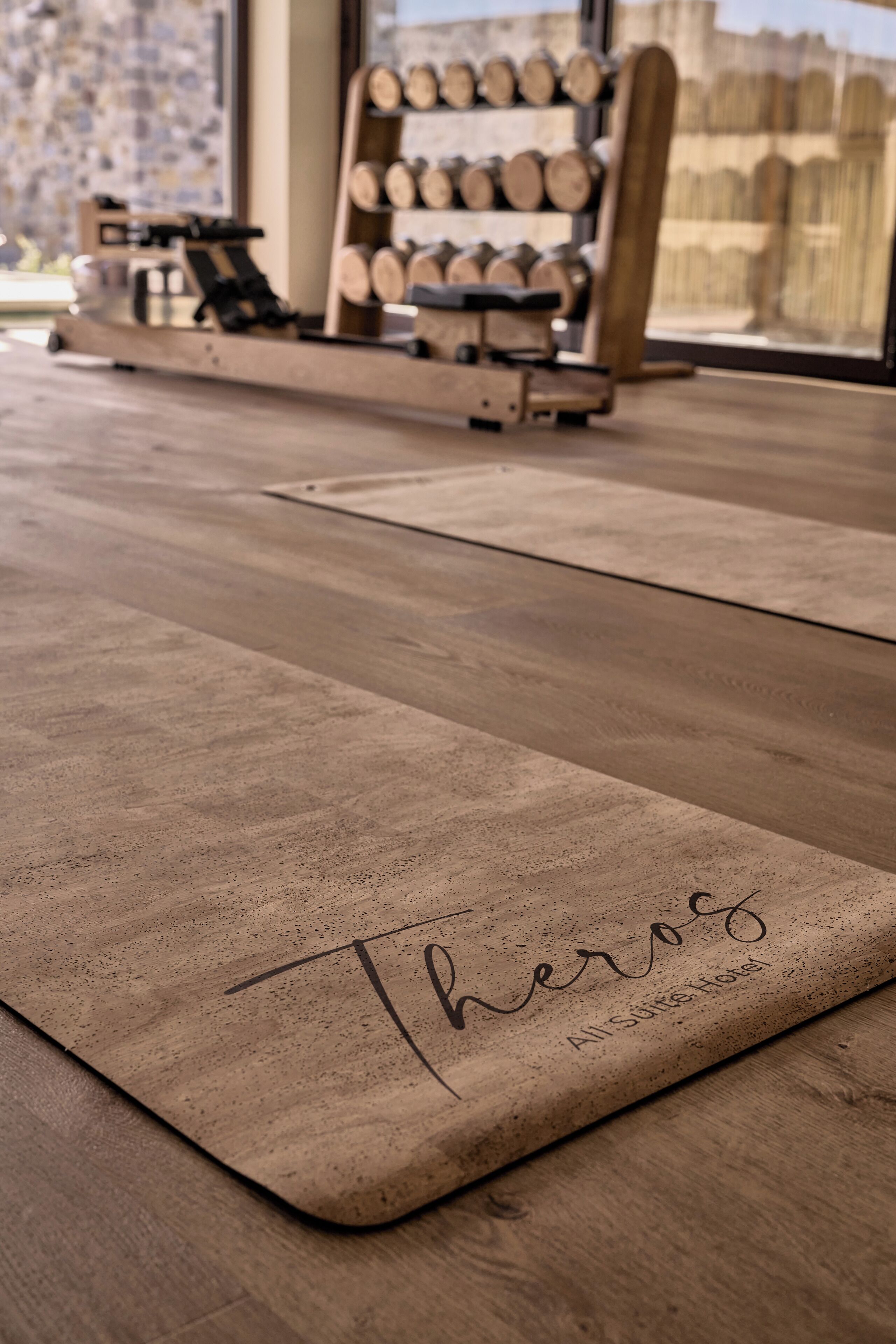 A wooden floor with a mat that reads "Theros All Suites Hotel."
