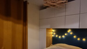 A bedroom with a bed, wooden headboard, and string lights.