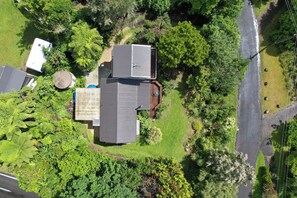 An aerial view of a residential area with multiple houses, a road, and surrounding greenery.