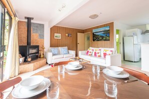 A modern living room with a fireplace, white sofas, and a dining table set for four.