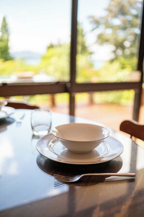 A dining table with a bowl and a glass, set for a meal. - The Enclave - Lake Tarawera Views, Sleeps 6 (Rotorua)
