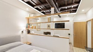 A modern bedroom with a bed, bedside table, and a wooden wardrobe. - Ciancaleoni Studio Atelier of the Artist - Monti (Roma)