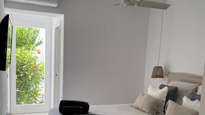 Un dormitorio con cama, almohadas, ventilador de techo y ventana.